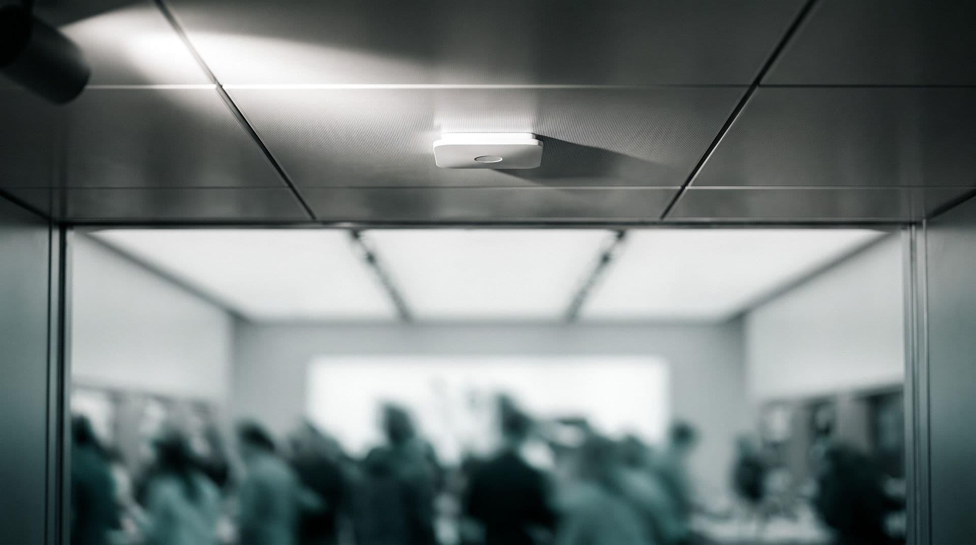 Illustrative photo: a ceiling-mounted radar sensor above a store entrance