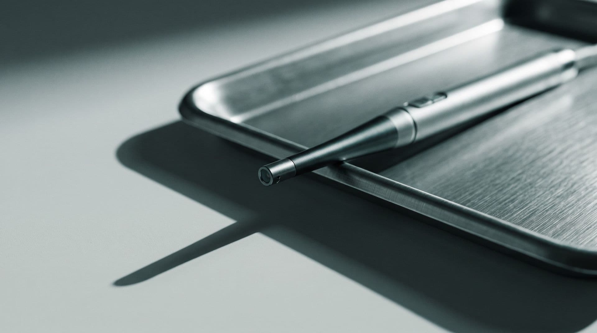 Illustrative photo: a handheld intraoral camera probe on a dental instrument tray