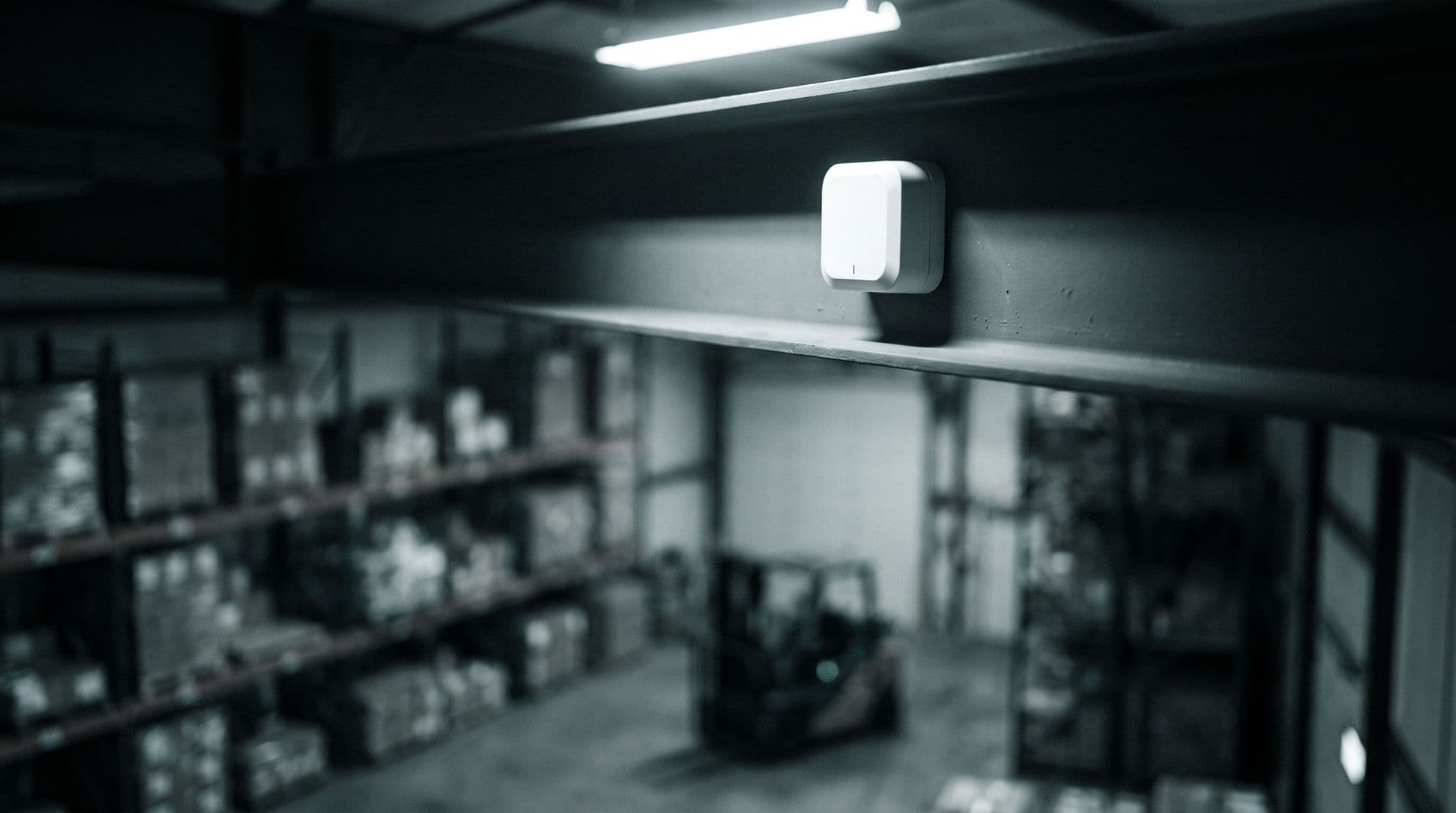 Illustrative photo: an ultra-wideband positioning anchor mounted in a warehouse