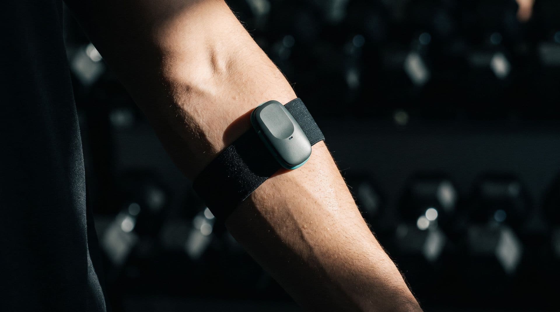 Illustrative photo: a wireless muscle-activity sensor worn on a forearm in a gym